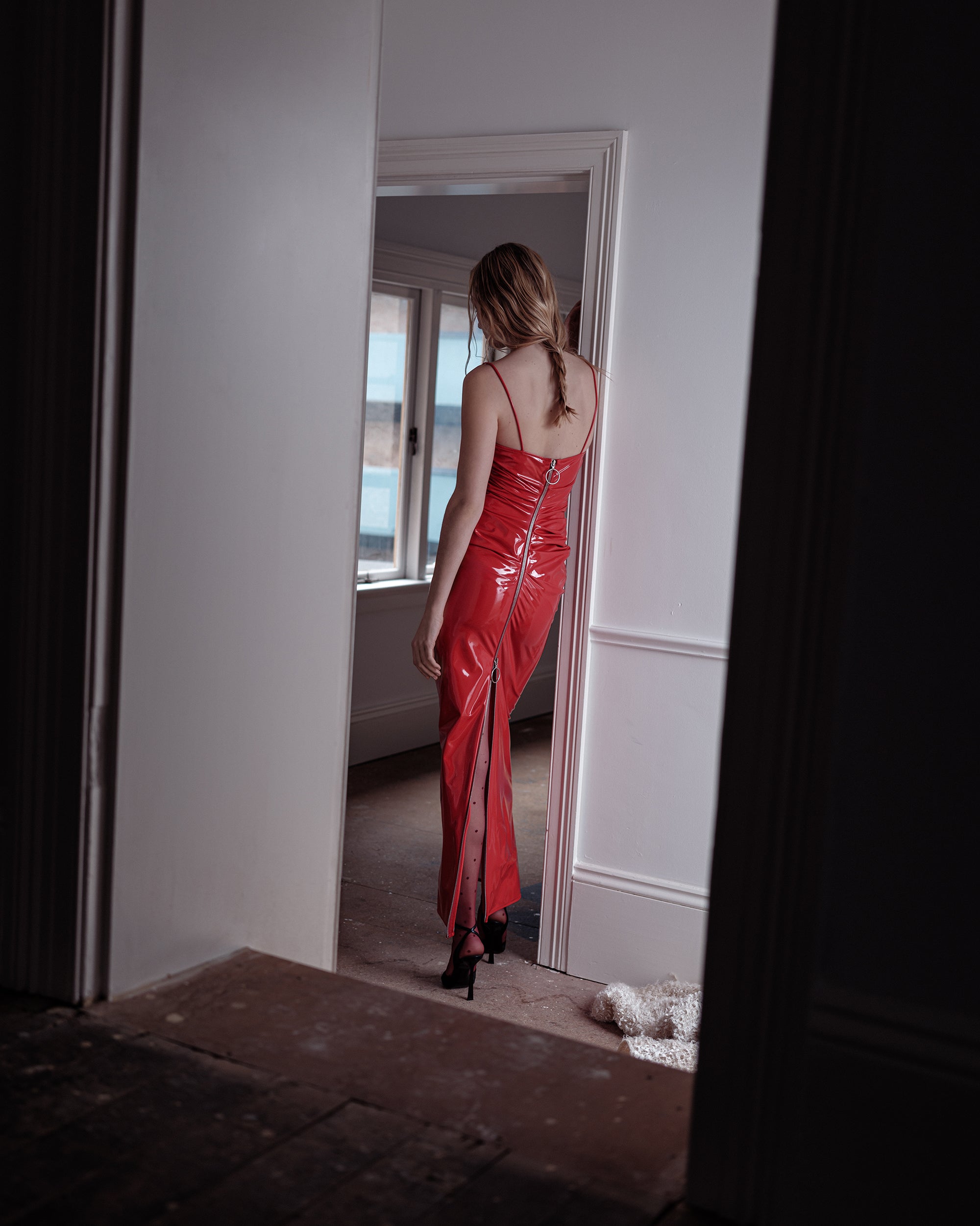 Woman in a Candy red Common Hours Nip PVC dress standing in a doorway.