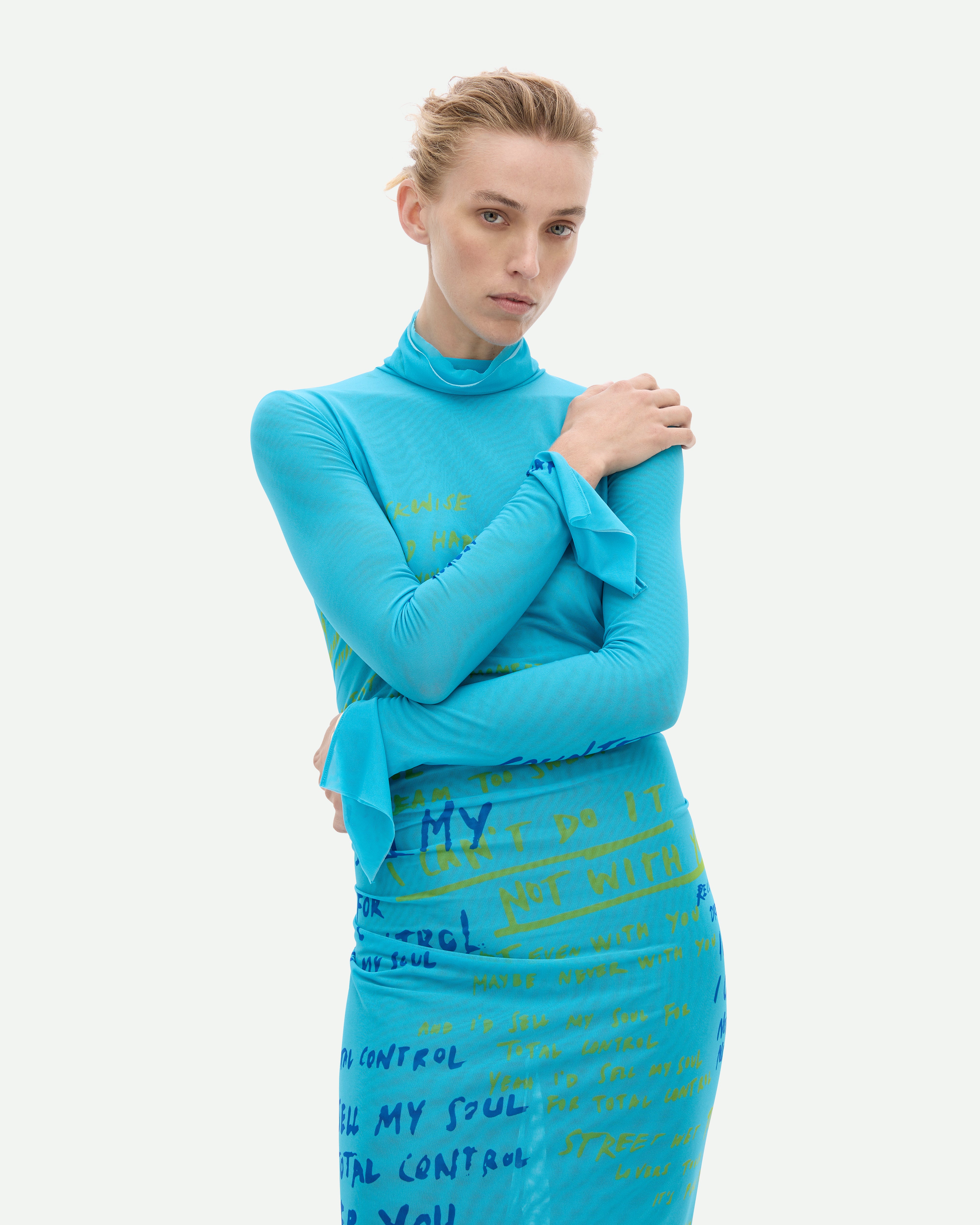 A long turquoise mesh dress with a placement print, featuring a high neck and long sleeves.