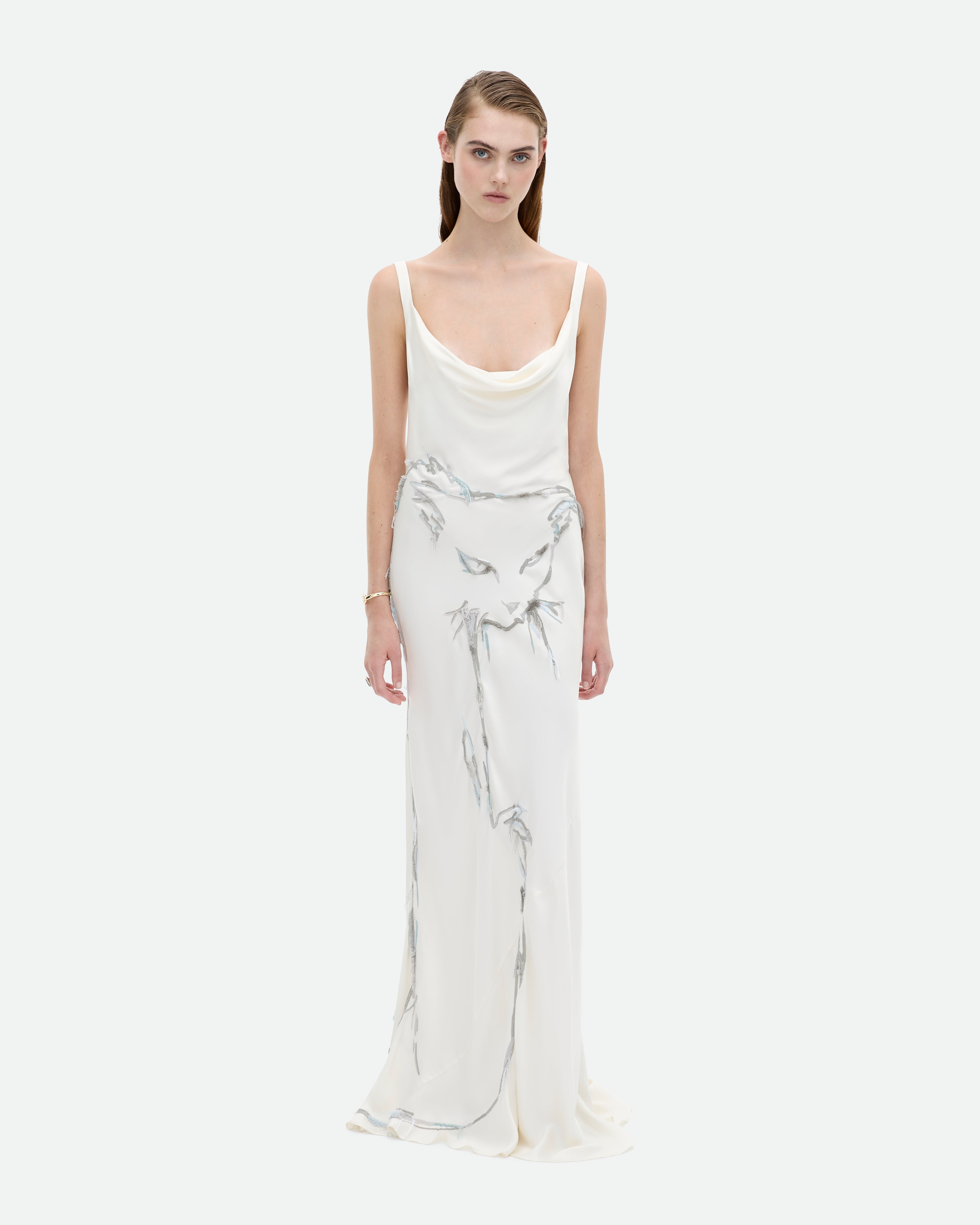A woman wearing a white, cowl neck, bias cut gown from Common Hours with cat hand-embroidery.