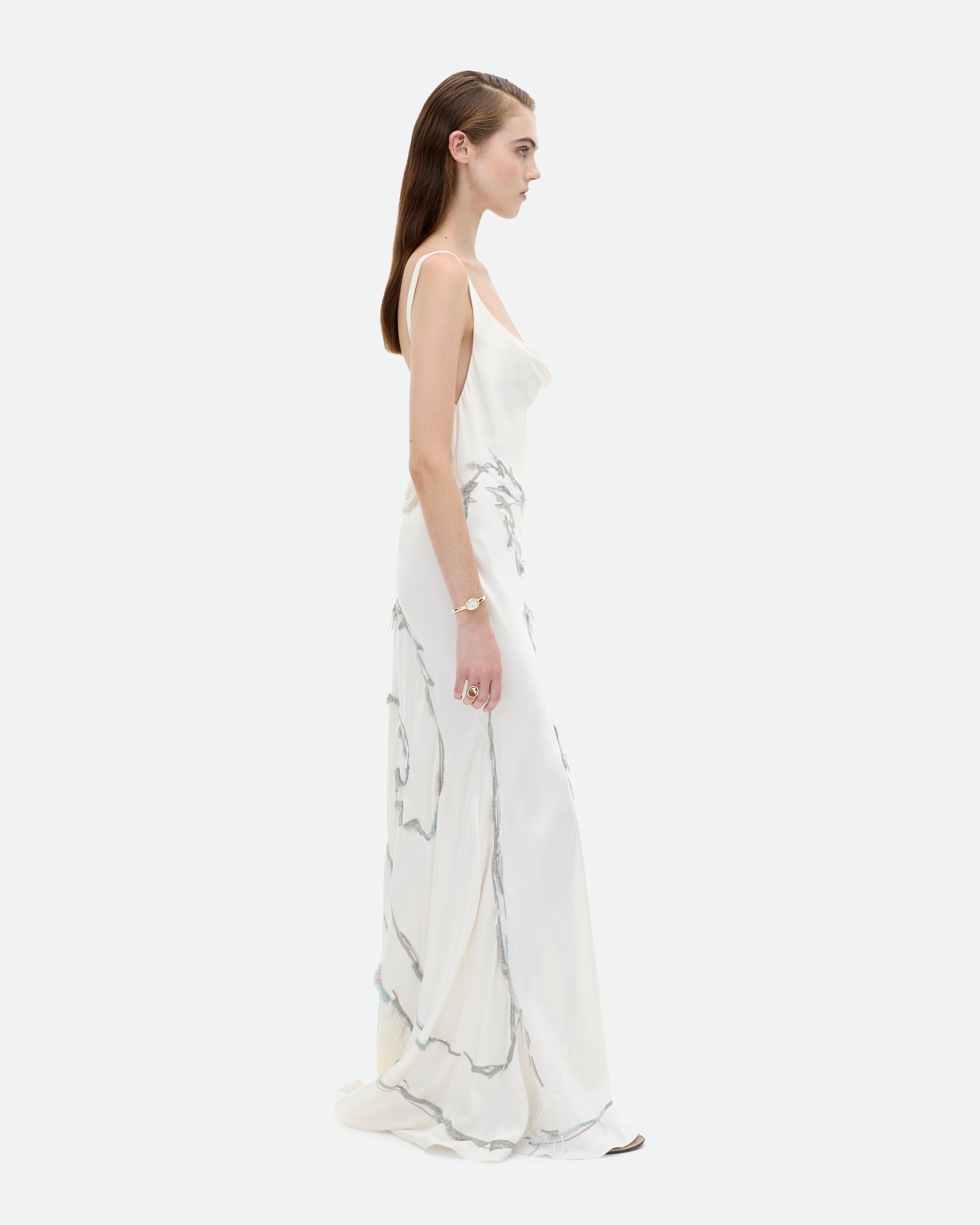 A woman wearing a white, cowl neck, bias cut gown Rapture from Common Hours with cat hand-embroidery.