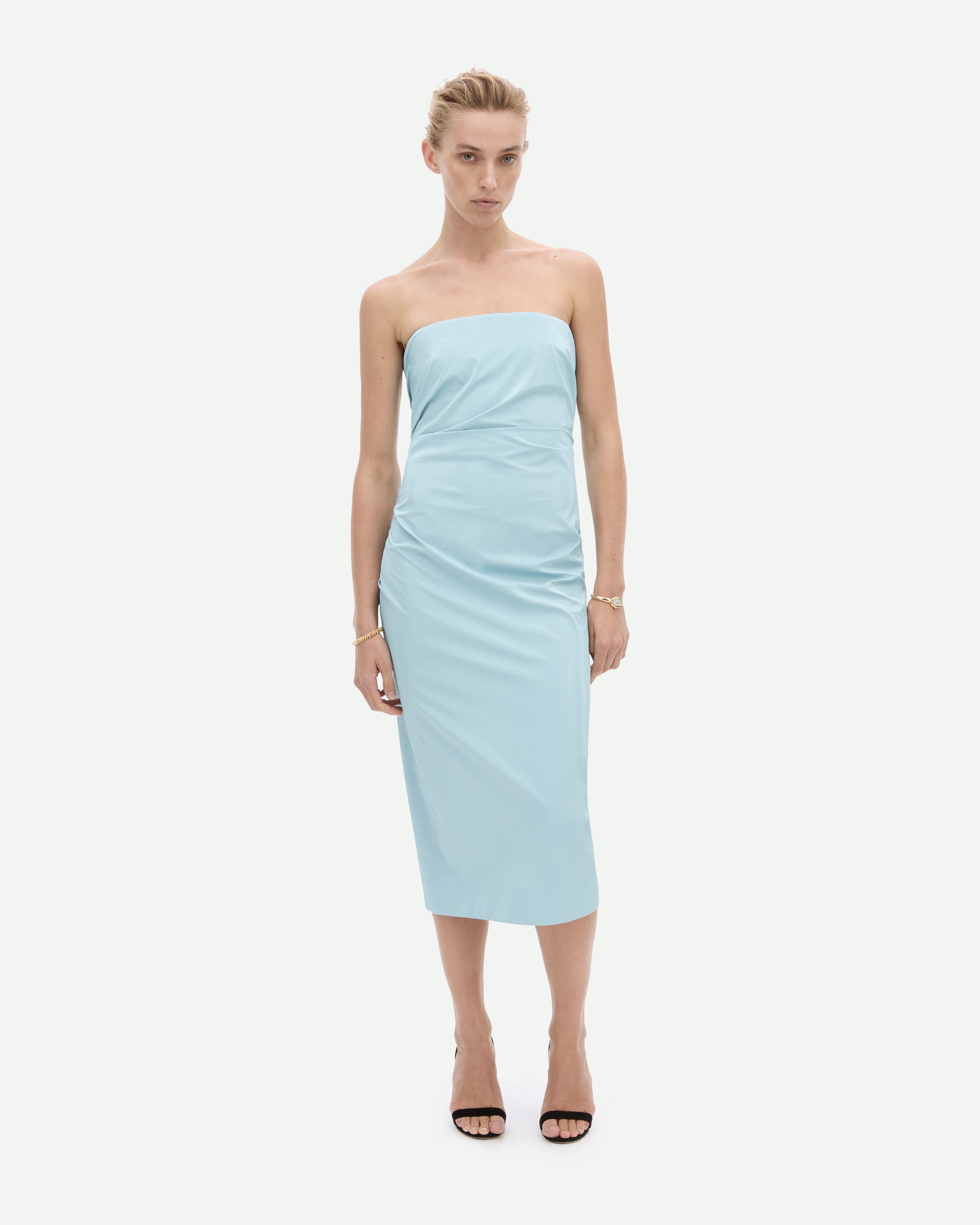 A woman wearing a strapless, sky blue, mid-length dress with a fitted silhouette, Tabloid dress by Common Hours.