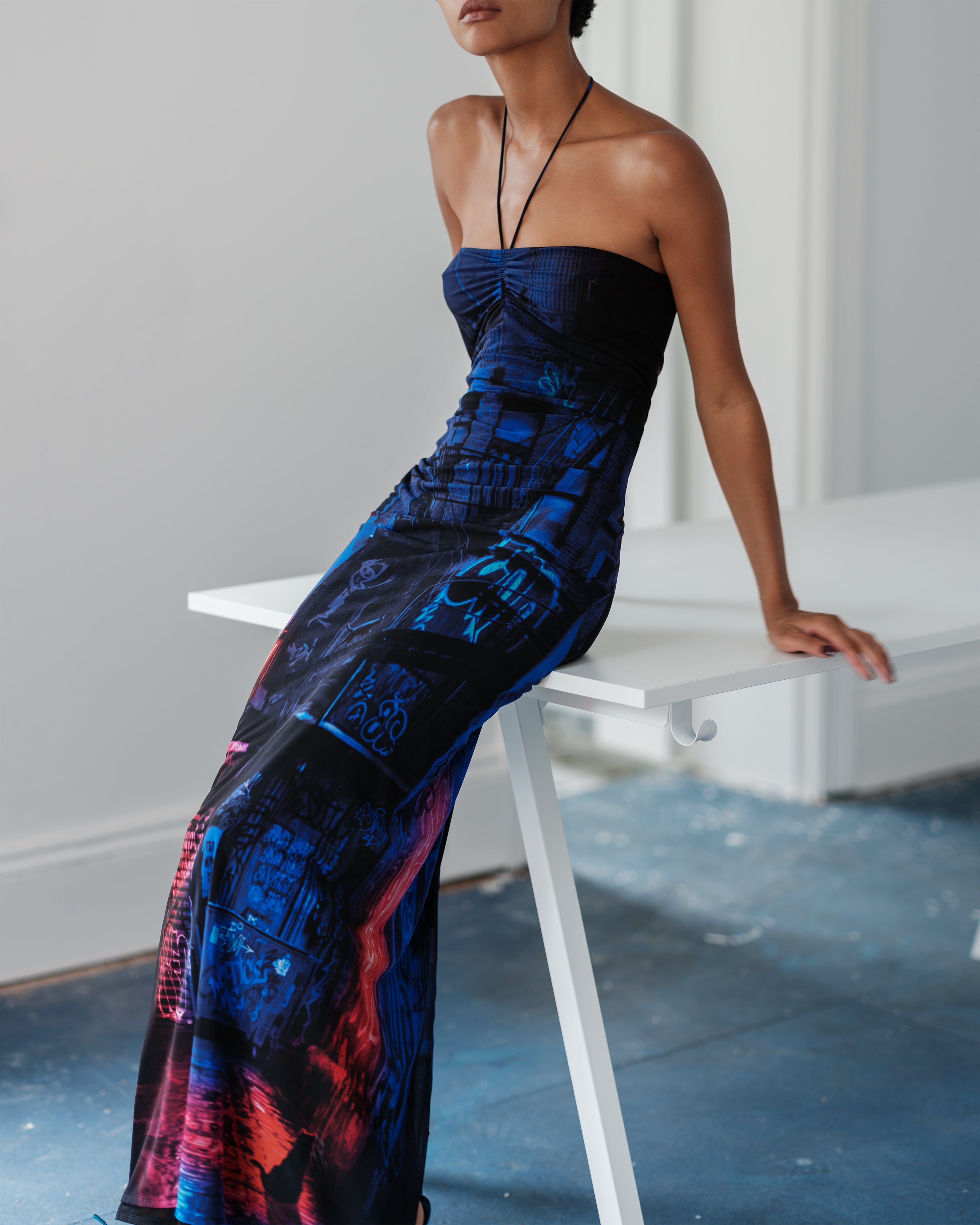 Woman wearing a Common Hours Just Us strapless, long, dress sitting on a white table.