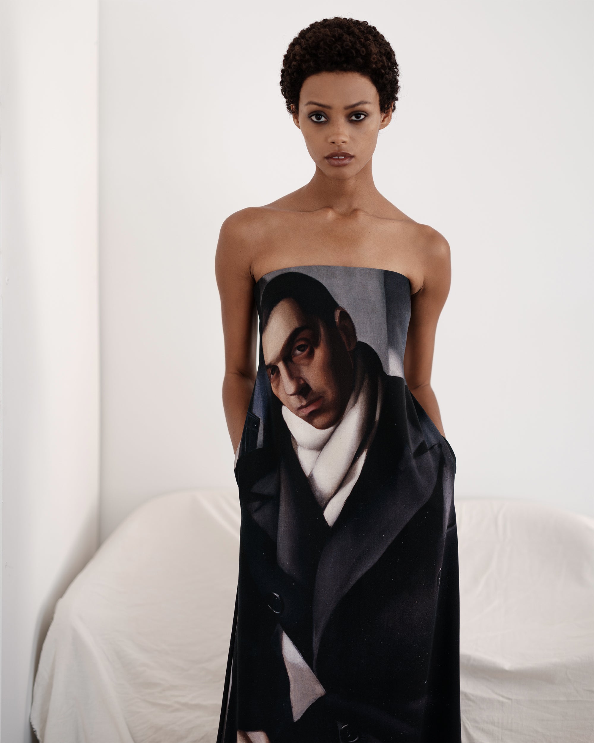 Model wearing a long black strapless dress featuring a painting of a man by Common Hours.
