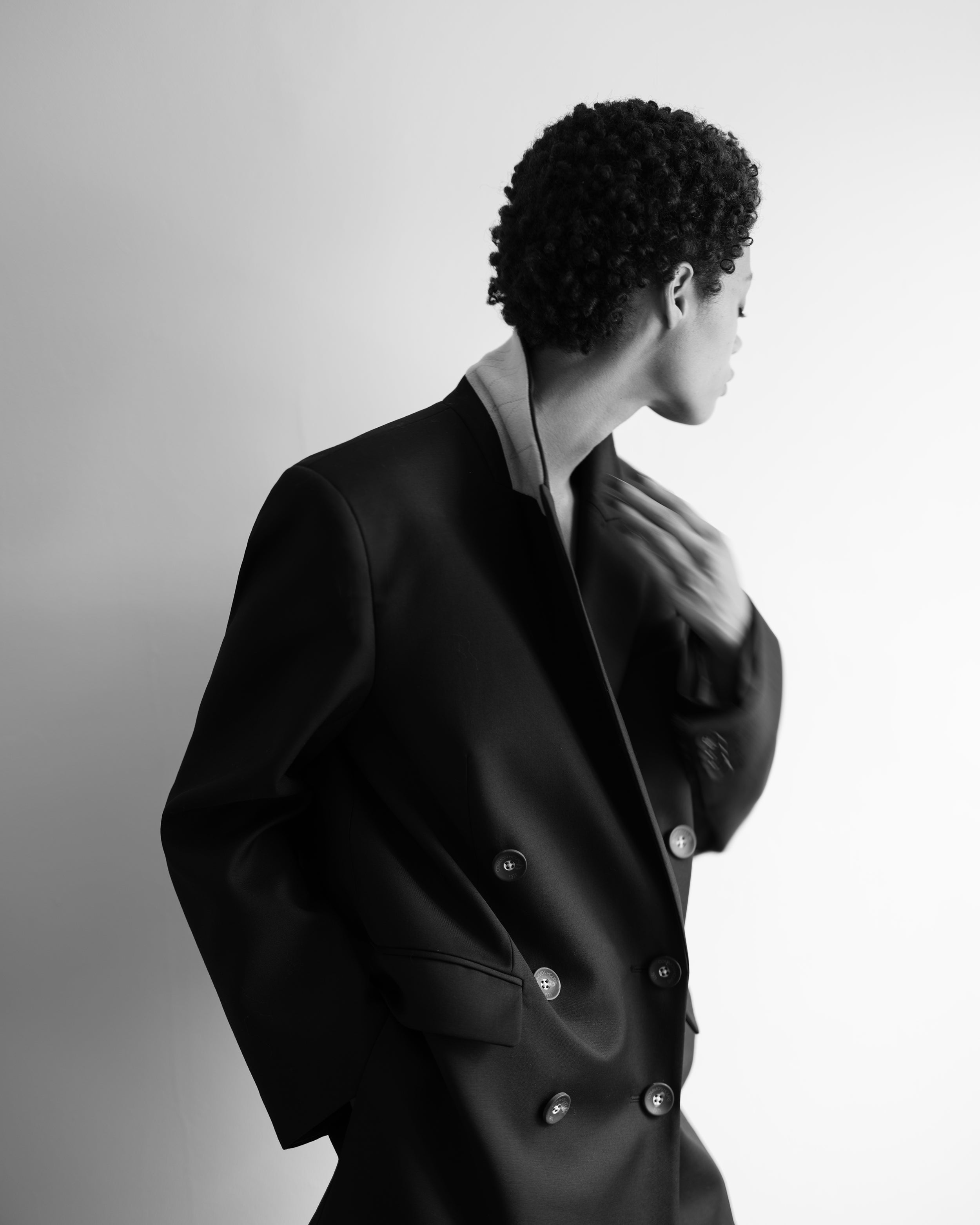 Woman wearing a black Common Hours blazer dress against a gray background