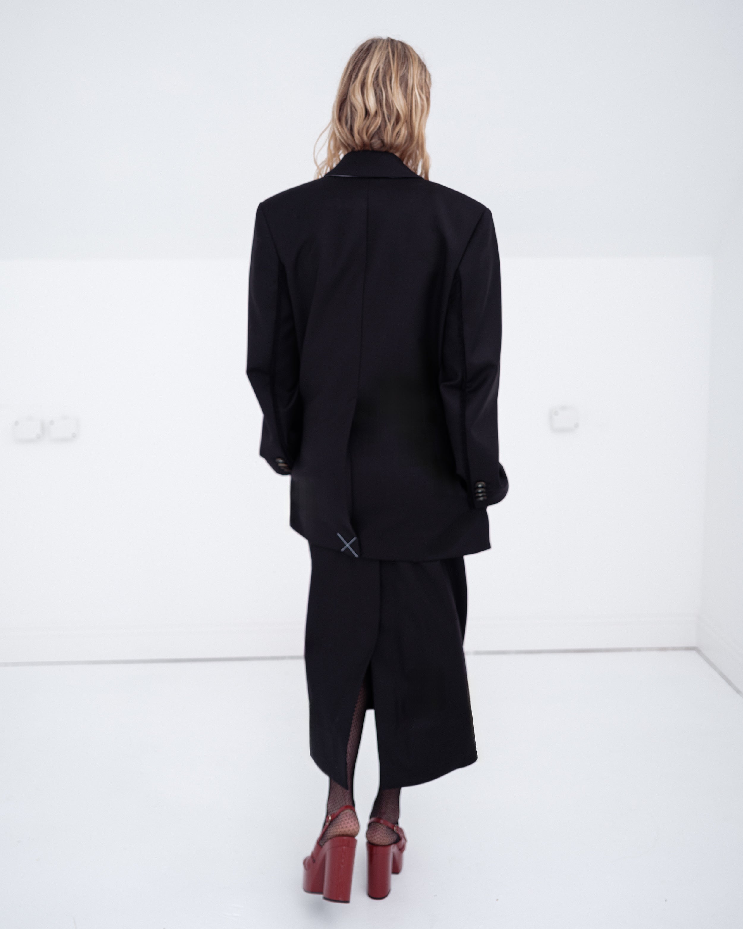 Woman wearing a black Common Hours blazer dress and matching strapless dress on a white background